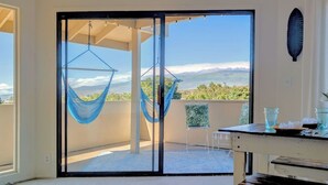 A balcony with a hammock, a table with glasses, and a view of the landscape.
