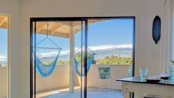 Un balcón con una hamaca, una mesa con vasos y vistas del paisaje.