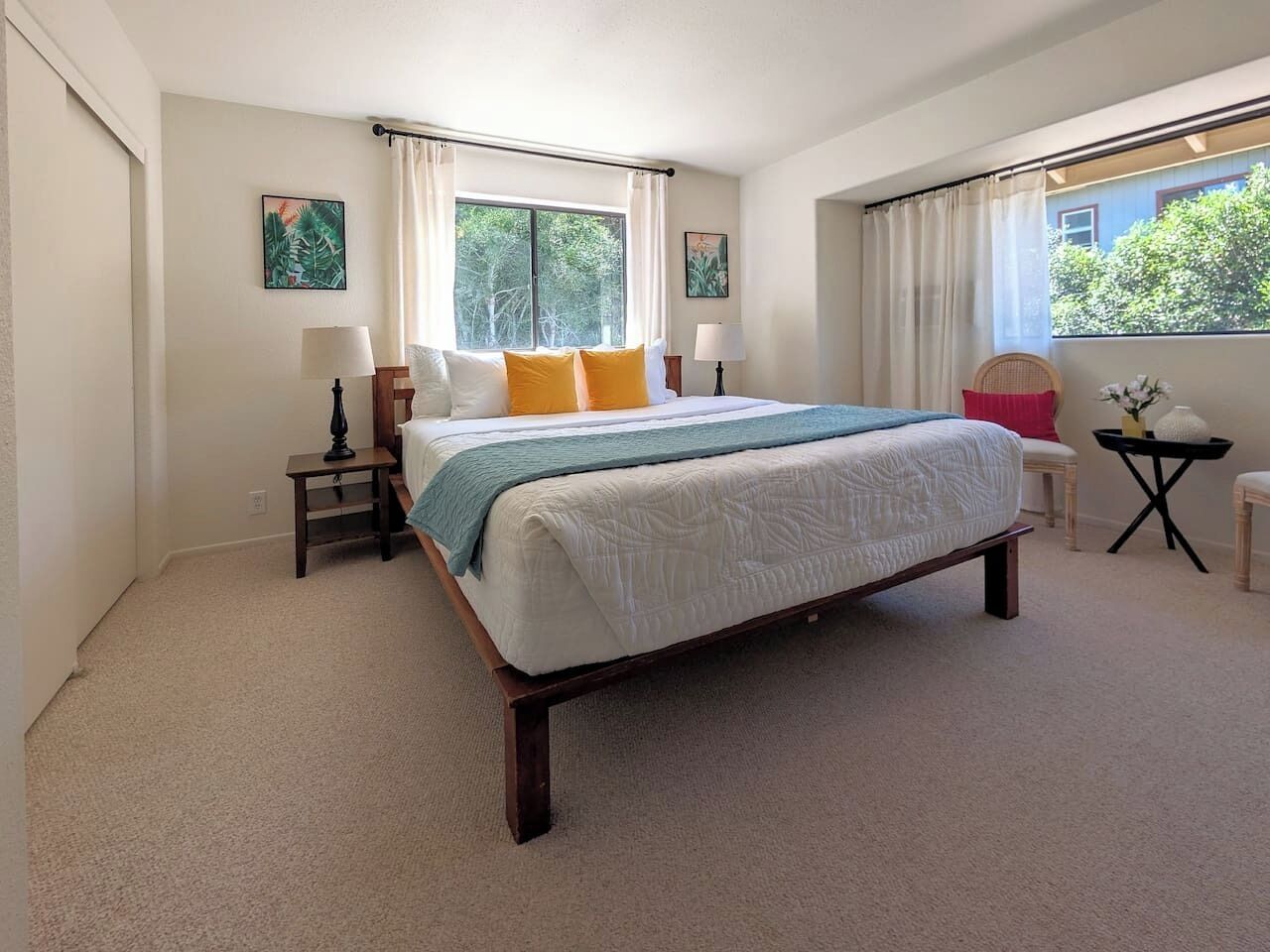 Une chambre à coucher avec un grand lit, deux tables de chevet, une chaise et une fenêtre avec des rideaux.