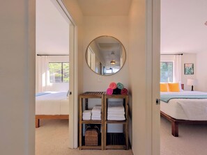 A bedroom with a bed, a bedside table, a lamp, and a mirror.