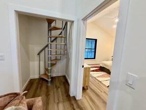 Eine Treppe führt zu einem Schlafzimmer mit einem Bett und einem Fenster.