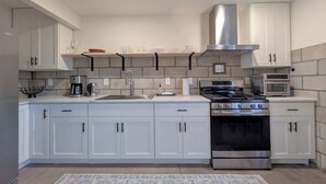 A modern kitchen with white cabinets, a stainless steel stove, and a microwave. - Hale Maluhia, Newly renovated, 1BR, sleeps 3. (Waikoloa Village)