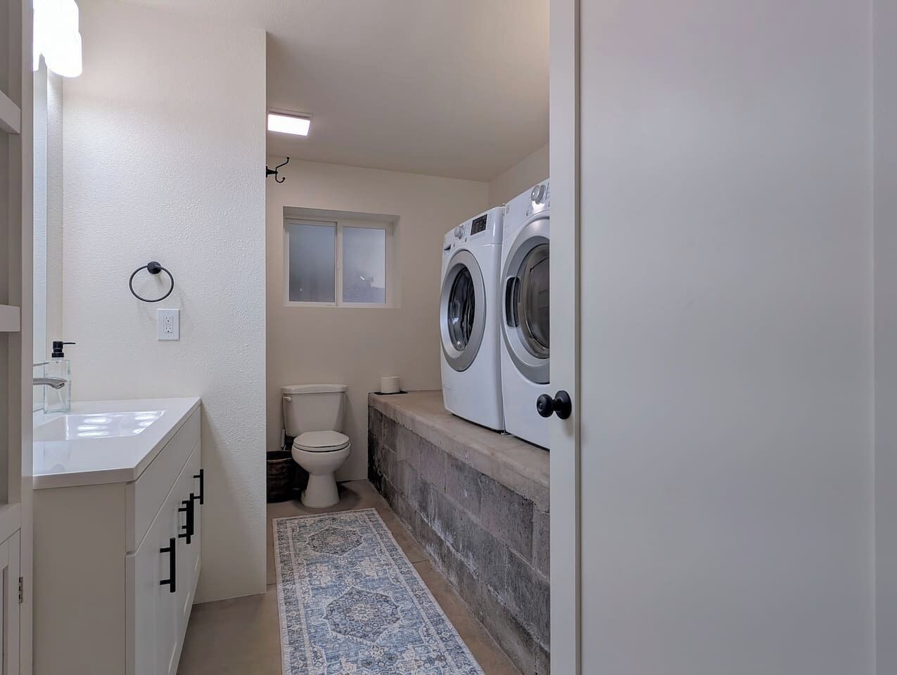 Un baño pequeño con inodoro, lavamanos y lavadora.