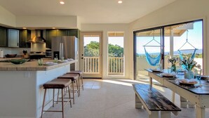 Une cuisine moderne avec un coin bar, une table à manger pour deux personnes et un balcon avec vue.