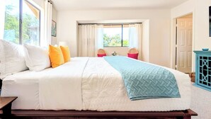 Une chambre à coucher avec un grand lit, un banc en bois et une vue sur l’extérieur par une fenêtre.