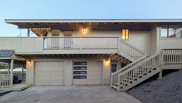 Une maison à deux étages avec un porche avant couvert, un garage et un escalier menant à l’étage supérieur.