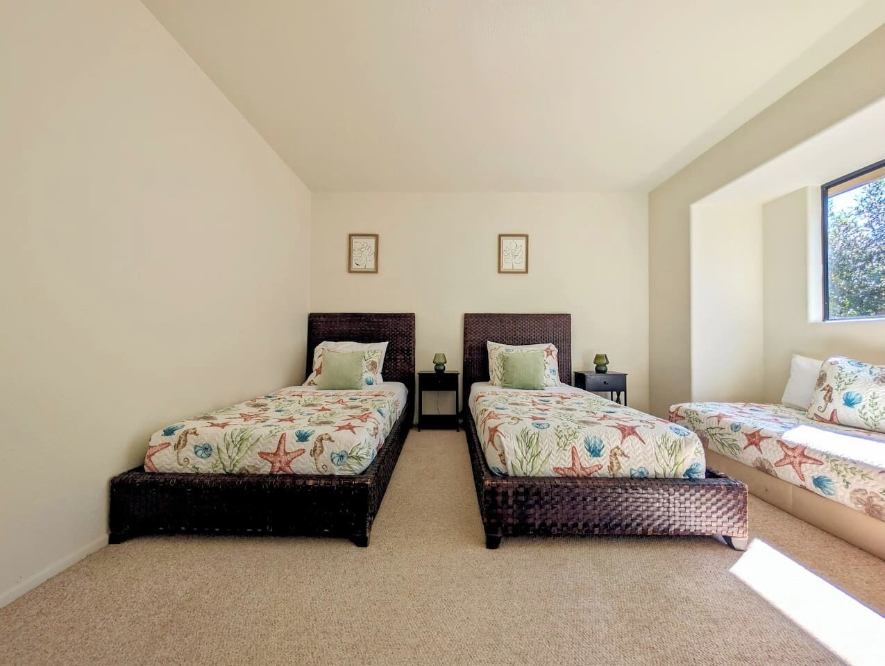 Un dormitorio con dos camas individuales, una mesita de noche pequeña y una ventana.