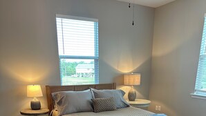 Quarto com uma cama, duas mesas de cabeceira, uma janela e uma porta.