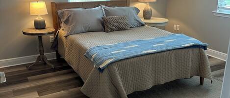 Une chambre à coucher avec un lit, deux tables de chevet, une fenêtre et une porte.