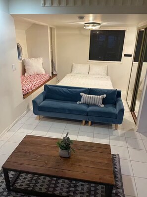 Ein gemütliches Schlafzimmer mit einem Bett, einem blauen Sofa, einem Holztisch und einem Topfpflanzen.
