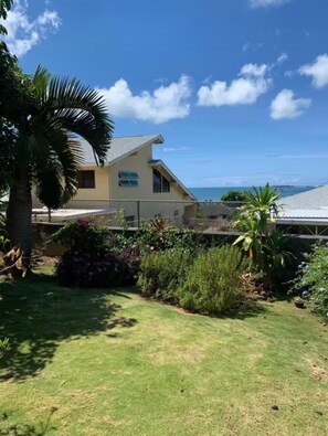 Una propietat residencial amb gespa, diferents plantes i vista a l'oceà.