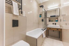 Een moderne badkamer met een douchecabine van glas, een witte badkuip en een wastafel met spiegel.