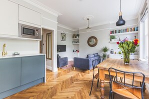 Une cuisine moderne équipée d’un four à micro-ondes, d’un évier avec un robinet doré et d’un coin repas comprenant une table et des chaises en bois.
