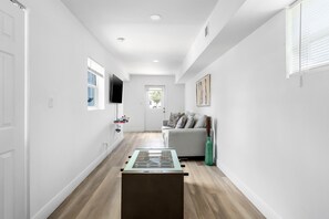 A hallway with a foosball table, a sofa, and a television on the wall. - Spacious 3BR Hollywood Home, Backyard & BBQ, Close to Beach & Hard Rock (Hollywood)