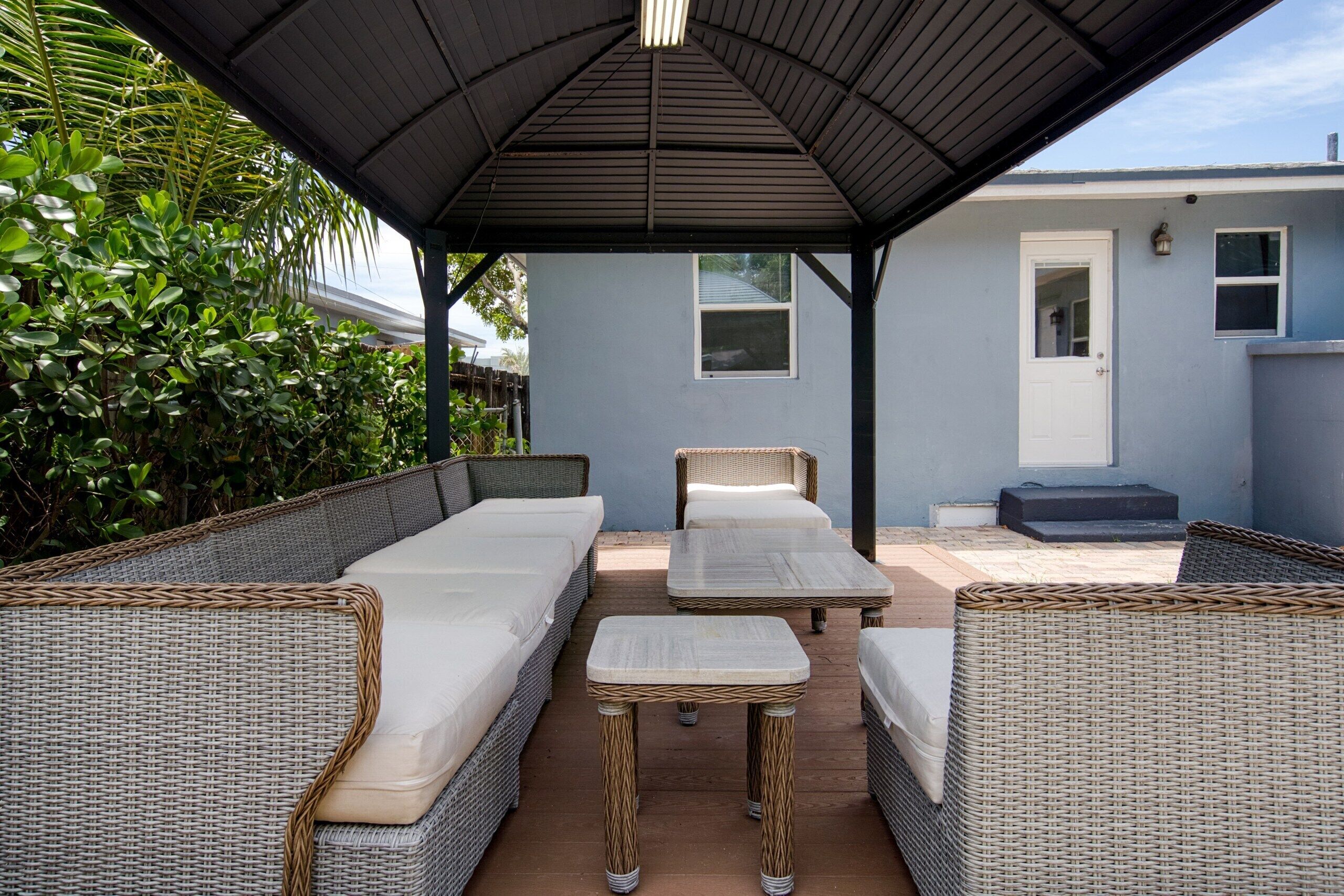 A covered outdoor seating area with wicker furniture and a table.