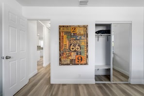 A hallway with a white door, a coat rack, and a wall-mounted artwork. - Spacious 3BR Hollywood Home, Backyard & BBQ, Close to Beach & Hard Rock (Hollywood)