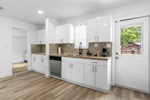 A modern kitchen with white cabinets, granite countertops, and a dishwasher. - Spacious 3BR Hollywood Home, Backyard & BBQ, Close to Beach & Hard Rock (Hollywood)