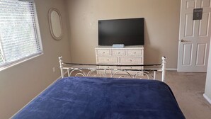 A bedroom with a bed, a dresser, a television, and a door labeled 'ROOM 5'. - Goodyear 2 Story (Goodyear)