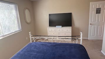 Un dormitorio con una cama, un aparador, un televisor y una puerta con la inscripción 'ROOM 5'.