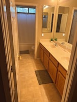 Un baño con lavamanos doble, armarios de madera, un espejo y una ventana.