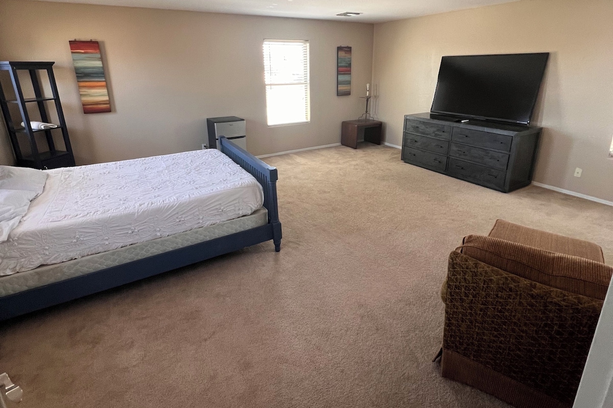 A bedroom with a bed, a TV, a dresser, and a window.