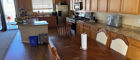 A kitchen with wooden cabinets, a stainless steel refrigerator, a microwave, and a toaster.
