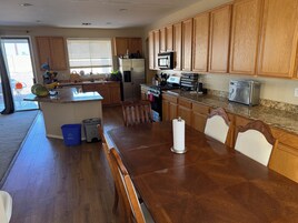 Una cocina con armarios de madera, un refrigerador de acero inoxidable, un microondas y un tostador.