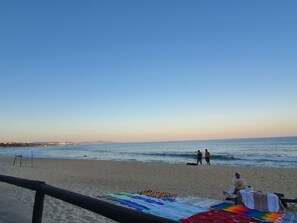 A beach with a wooden fence, a colorful blanket, and a few people. - Ocean view endless.  Walk to beach. 1bdrm (San José del Cabo)