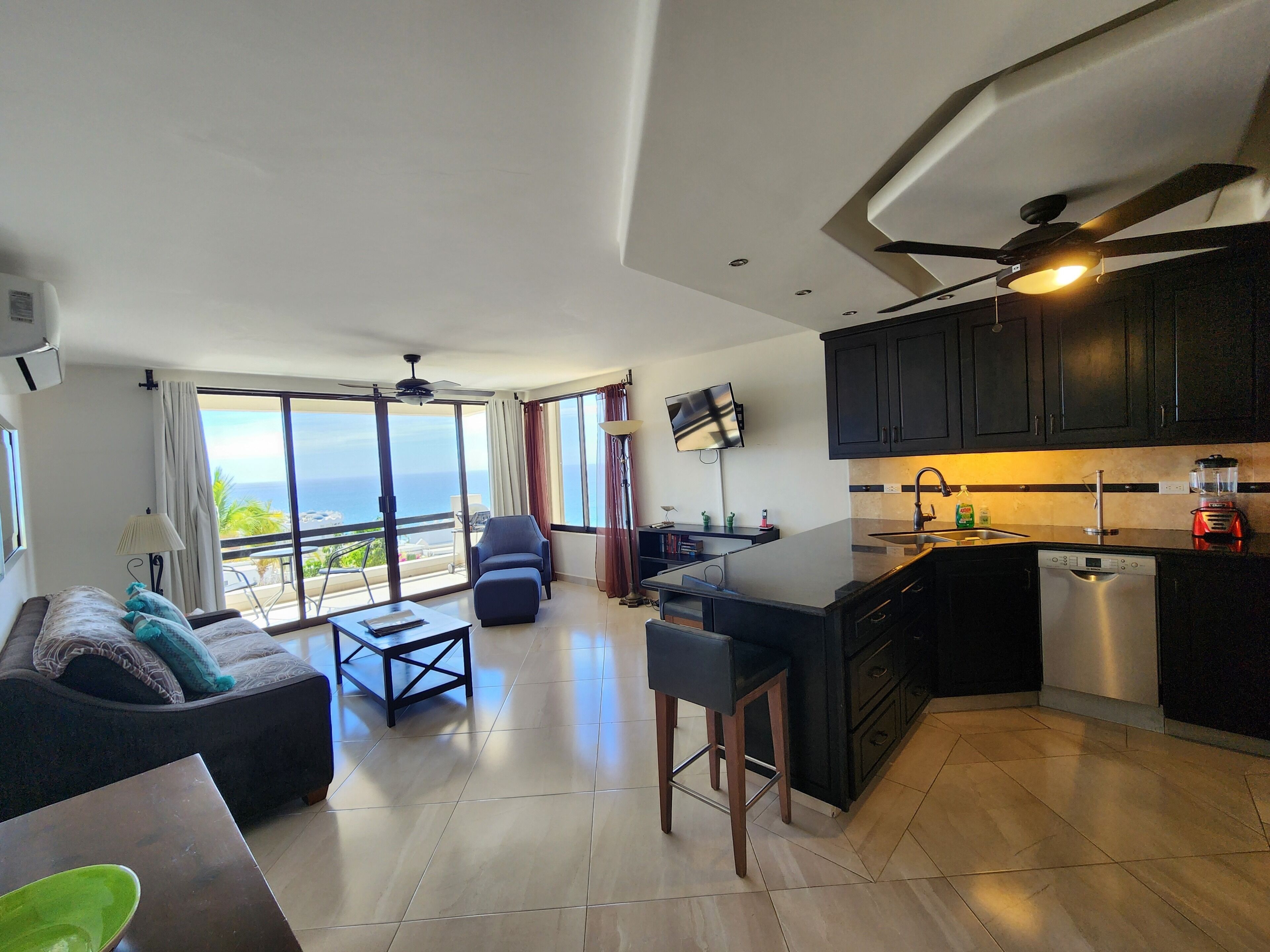 A modern living space with a balcony, a kitchen area, and a seating area with a view.
