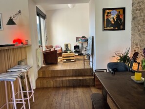 A modern living room with a wooden floor, a brown leather sofa, a coffee table, and a painting on the wall. - SMALL STONE & WOOD HOUSE (Blainville-sur-Mer)