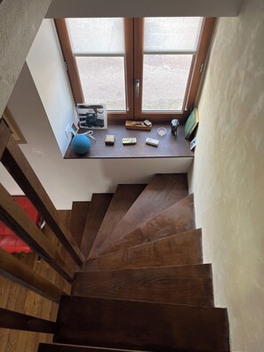 Eine Holztreppe führt zu einer Zwischenebene mit einem Fenster darüber.