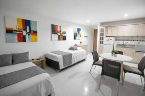 A modern hotel room with two beds, a dining table, and a kitchen area. - Studio 1309—perfect for 2 or 4 people (Cartagena de Indias)