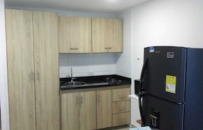 A compact kitchen with wooden cabinets, a black countertop, and a black refrigerator. - Studio 1309—perfect for 2 or 4 people (Cartagena de Indias)