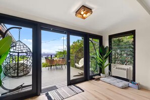 Ein modernes Interieur mit einer großen Schiebeglastür, die auf eine Terrassenfläche führt, einem Hängestuhl und einem Topfpflanzen.