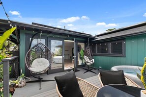 A deck with two hanging chairs, a table, and an inflatable pool. - Kaneohe Bay Hale (Kaneohe)