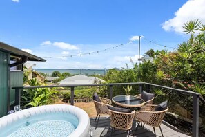 Ein Balkon mit einem Whirlpool, Korbstühlen und Meerblick.
