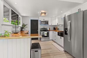 Eine moderne Küche mit weißen Schränken, Edelstahlgeräten und einer Holzausziehtafel.