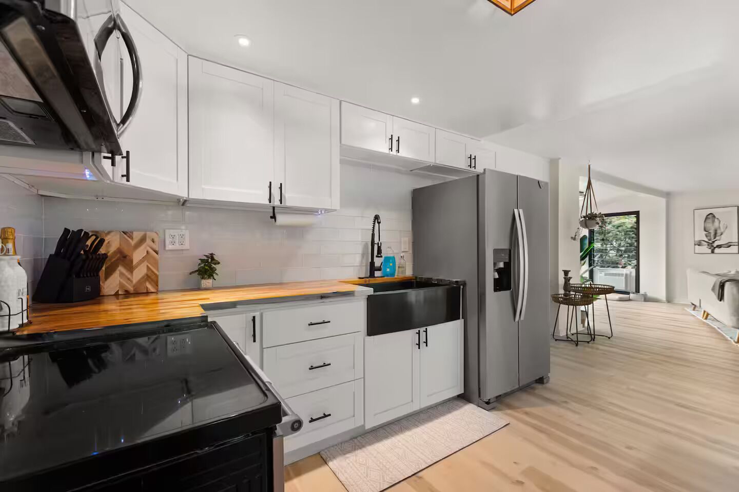 A modern kitchen with white cabinets, a black countertop, and a stainless steel refrigerator.