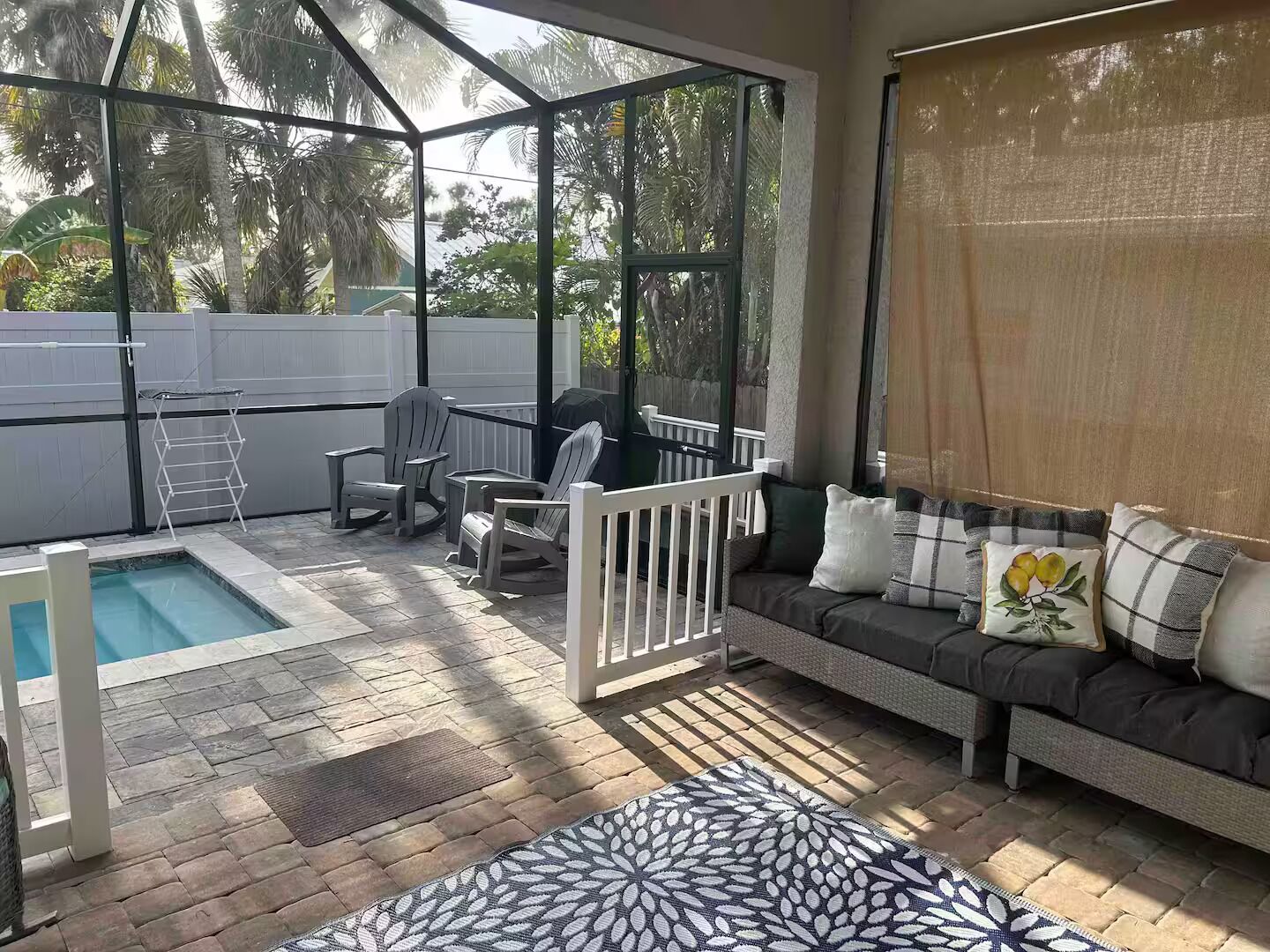 A covered patio with a pool, seating area, and a view of the backyard.