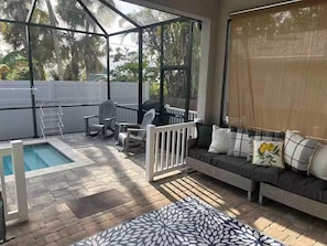 A covered patio with a pool, seating area, and a view of the backyard.