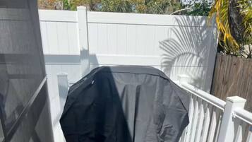 Una terraza techada con barandal blanco.
