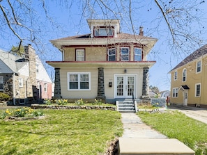 A two-story house with a stone facade, a front porch, and a visible address number.