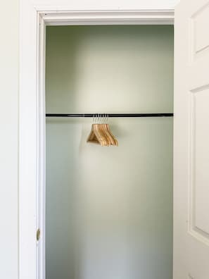 A closet with a wooden hanger rod and a single wooden hanger.