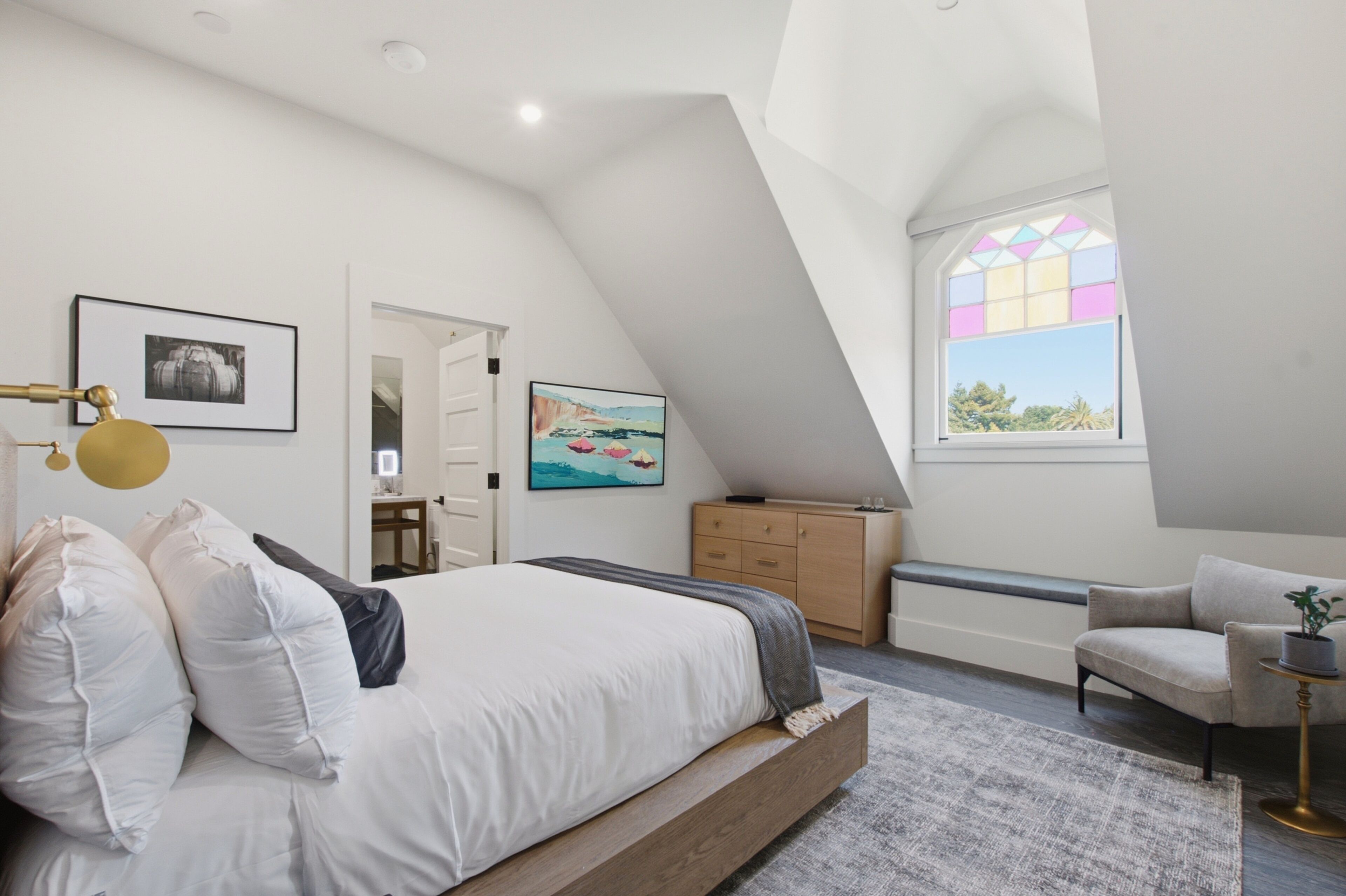 A bedroom with a bed, a dresser, a chair, a desk, and a window with a view.