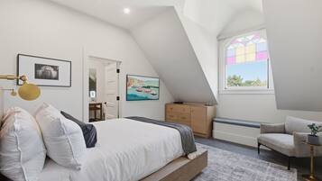 A bedroom with a bed, a dresser, a chair, a desk, and a window with a view.