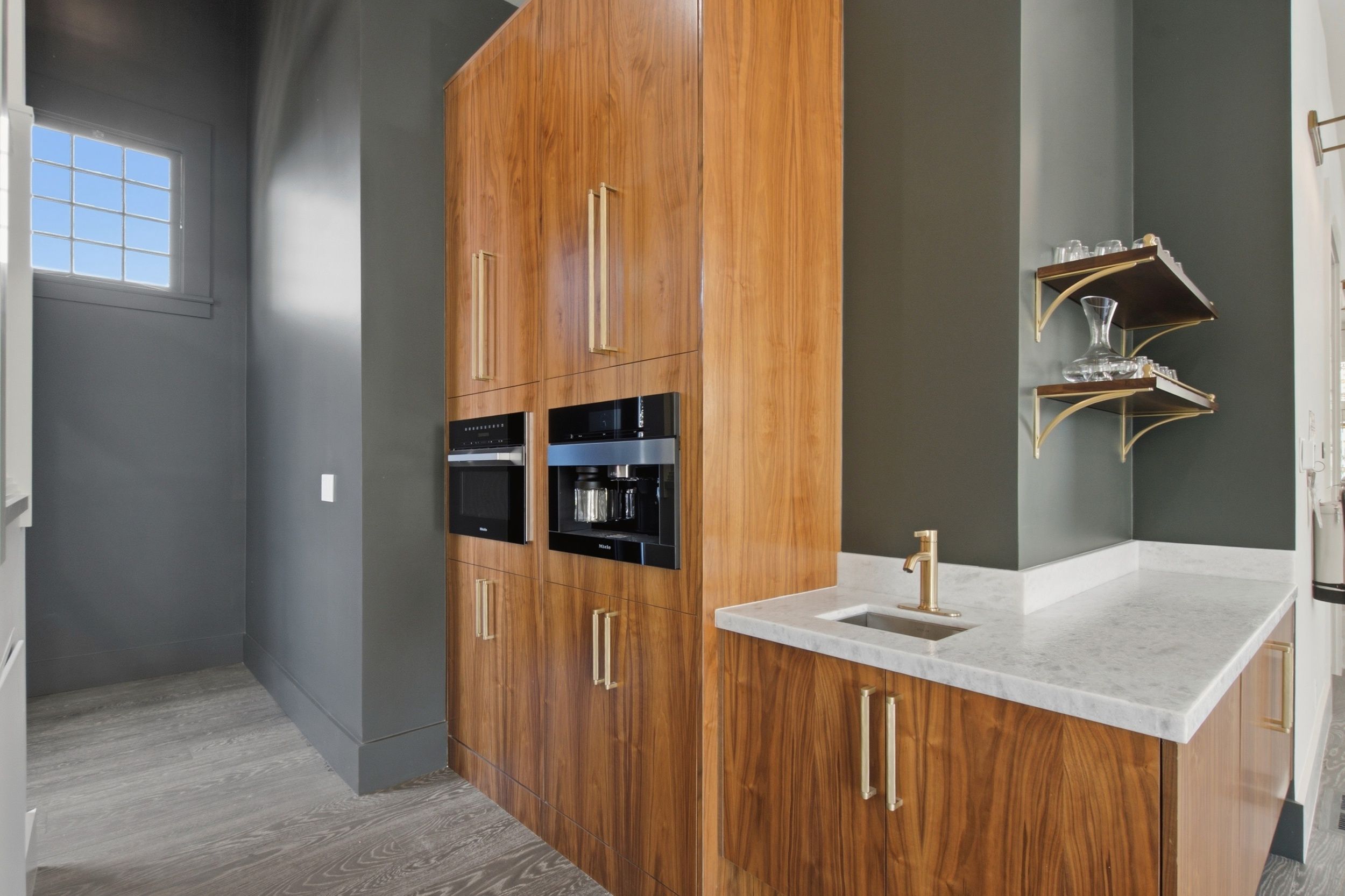 Una cocina moderna con armarios de madera, encimera de mármol y horno empotrado.