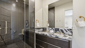 A modern bathroom with a large mirror, dark wood vanity, and a glass shower enclosure.