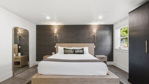 Un dormitorio moderno con una cama grande, dos lámparas de noche, un espejo y una ventana con vistas.