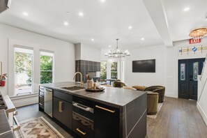 Una cocina moderna con una isla grande, electrodomésticos integrados y un comedor con candelabro.