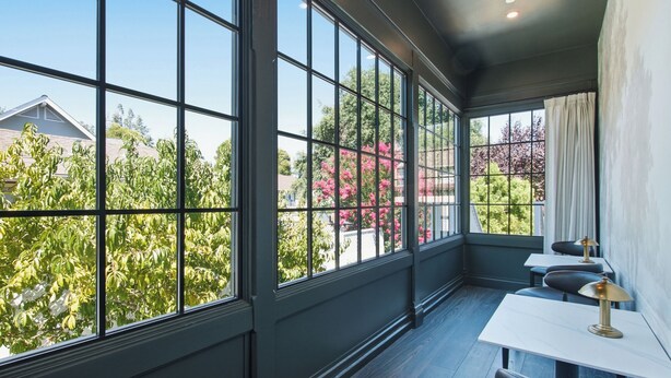 A room with large windows, a table, and chairs.